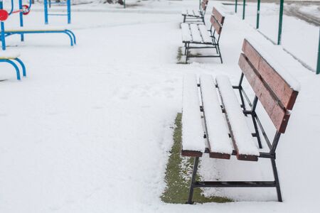 Benches for rest are covered with snow in the park in winterの写真素材