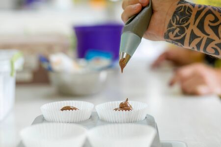Woman professional pastry chef spreads chocolate dough in baking dish.の写真素材