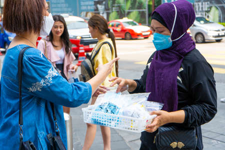 A girl with a plastic box sells protective medical masks on the street. Business during a pandemic virusのeditorial素材