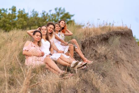 A cheerful company of beautiful girls friends enjoy a picturesque panorama of the green hills at...