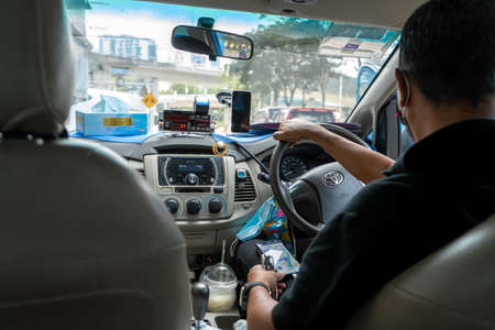 Asian taxi driver in a medical mask. The interior of an Asian taxi. View from the rear seat