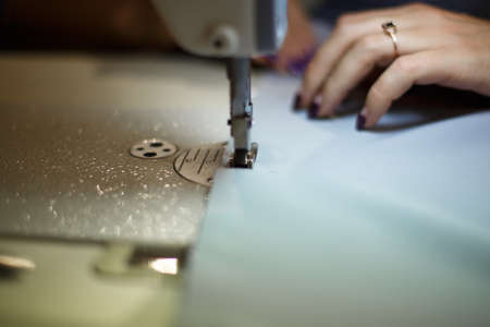 Workplace seamstress. Tailoring industry. Girl sews on the sewing machine. Factory clothing.の写真素材