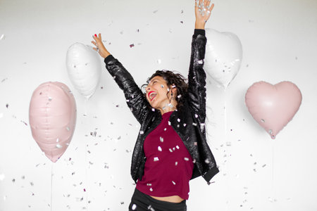 The emotion of success. Happy sexy brunette girl enjoying celebrating with confetti and heart...