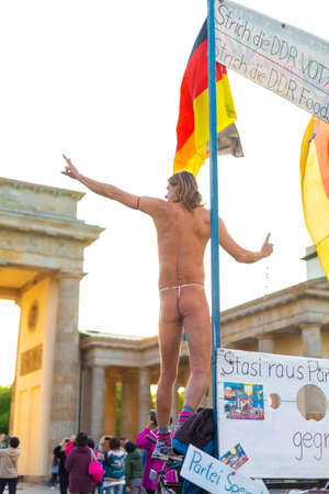 The crowd walks in the square in front of the Brandenburg Gate. Performance of a naked man. Berlin, Germany - 05.17.2019のeditorial素材