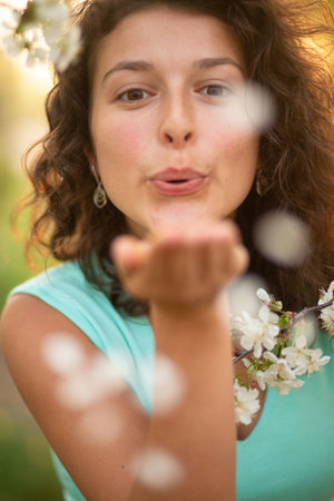 A young brunette girl poses with a blossoming cherry branch.の写真素材