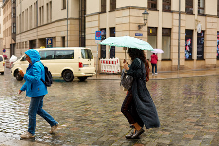 People with umbrellas run through a European city in the rain. Dresden, Germany - 05.20.2019のeditorial素材