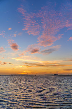 Incredible colors of the sunset sky with marshmallow clouds over the ocean.の写真素材