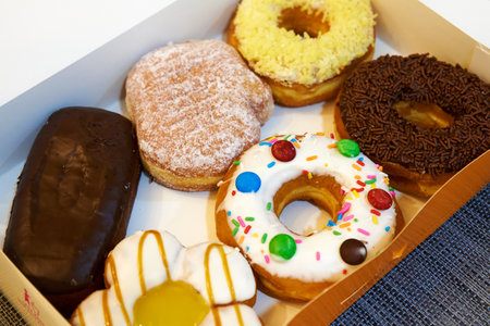 Box of sweets filled with colorful donuts and eclairs.の写真素材