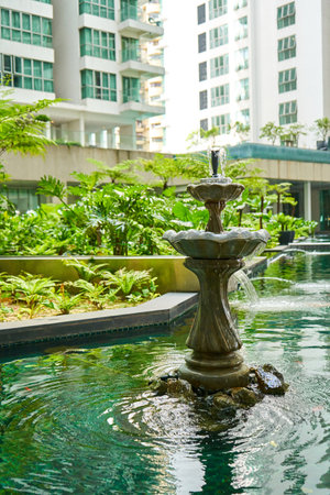 Fountain in the pond of residential building inner garden.の写真素材