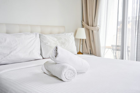 rolled up white towels on the hotel bed.の写真素材