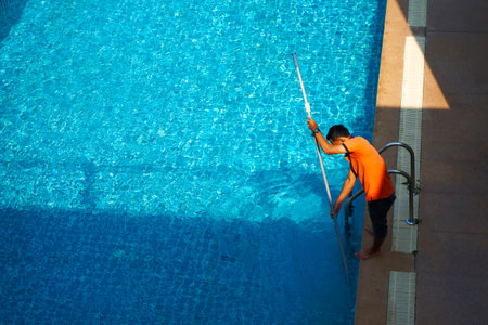 Top view of a worker cleaning a swimming pool in a private house in summer.のeditorial素材