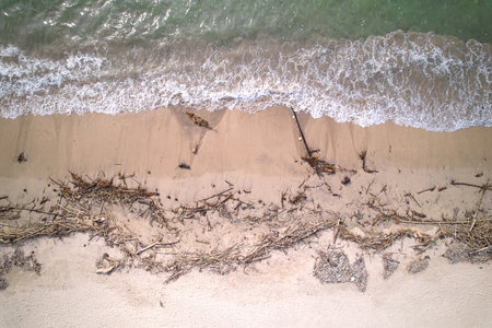 An top view of a polluted beach. Ocean waves bring garbage to the shore. The problem of ecology and pollution of nature and the planetの写真素材