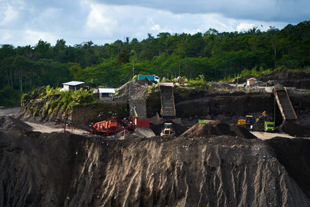A stone quarry in Indonesia. Large equipment such as bulldozers and dump trucks are working on the...
