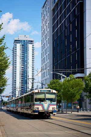 An older car of the lrt station streetcar train rides through the modern city of Calgary. Calgary, Alberta - 06.29.2023のeditorial素材