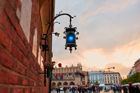 An old blue lantern made of handmade metal hangs on a brick wall in the historic streets of Krakow