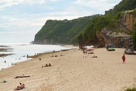 An incredibly beautiful deserted tropical beach under a cliff with clear, clean ocean water on the popular tourist island of Bali. Bali, Indonesia - 03.15.2018のeditorial素材