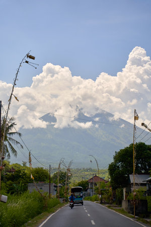View of the volcano from the road decorated for the holiday in the village. Bamboo decorations along the road. A panorama of Mount Agung covered in cloudsの写真素材