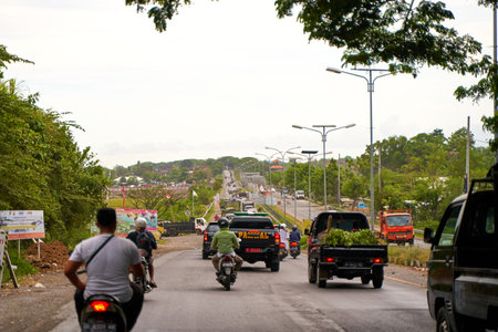Asphalt roads and traffic with cars and motorcycles on the island of Bali. A cozy way through Asian villages. Bali, Indonesia - 11/12/2022のeditorial素材