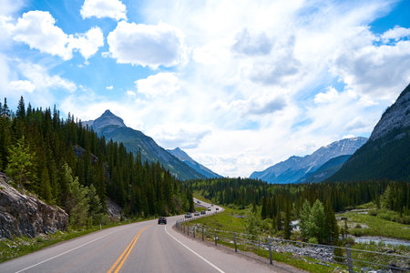 Beautiful view from a car on the Rocky Mountains in Banff National Park in Alberta. Panorama of a road in the mountains past a coniferous forest on a sunny day in summerの写真素材