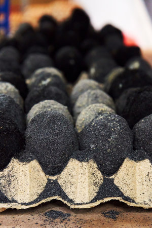 Black century-old Asian eggs in cardboard trays are in a warehouse in the storeの写真素材