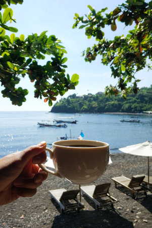 A mug of tea with a beautiful tropical ocean background.