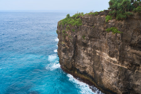 Cinematic aerial landscape shots of the beautiful island of Nusa Penida. Huge cliffs by the shoreline and hidden dream beaches with clear water and foaming waveの写真素材
