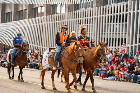 First Nations people ride horses during the Stampede Parade in Calgary. They wear traditional attire and share their culture with a large crowd. 07.07.2023 - Calgary, Canada
