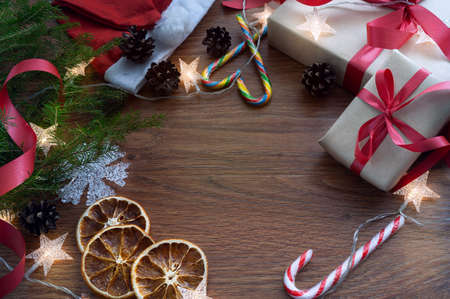 Christmas composition on a dark wooden background with a spruce branch, gifts, sweets, oranges and a...