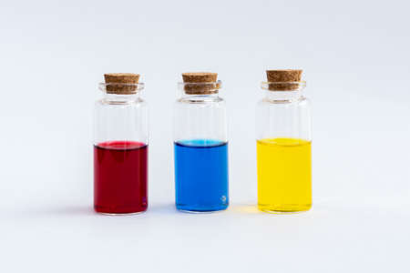 Three closed vials with colored contents on a white background. Red, blue, yellow. High quality photoの写真素材