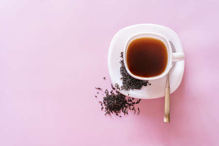 A Cup of tea with tea leaves on a pink background, top view. High quality photo