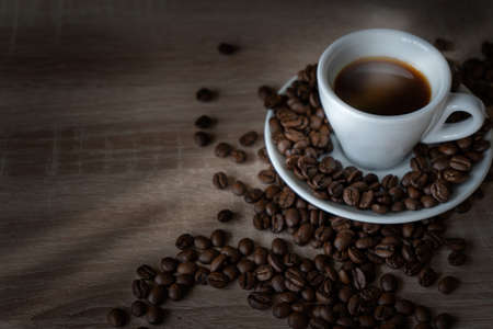 On the table is one Cup of coffee on a saucer with scattered coffee beans. High quality photo