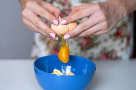 A girl breaks a chicken egg into a mixing bowl. High quality photo