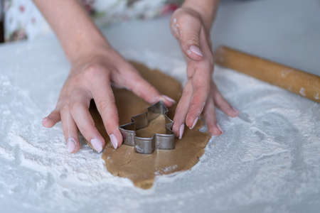 A girl cuts out cookies in the shape of a Christmas tree on the dough. High quality photo