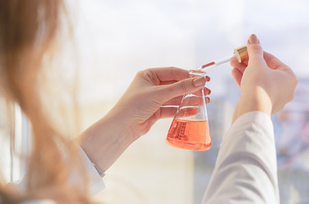 A girl laboratory assistant mixes reagents in the laboratory standing by the window. High quality...