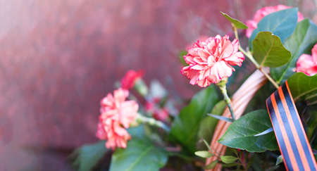 Basket with flowers carnations at the granite wall with St. George ribbon. High quality photoの写真素材