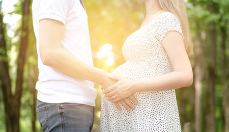 A pregnant woman and her man in the park in the rays of the sun. High quality photoの写真素材