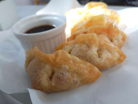 Fried dumplings with soy sauce on white tablecloth.