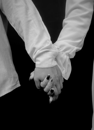 Black and white image of a couple holding hands on black background.の写真素材