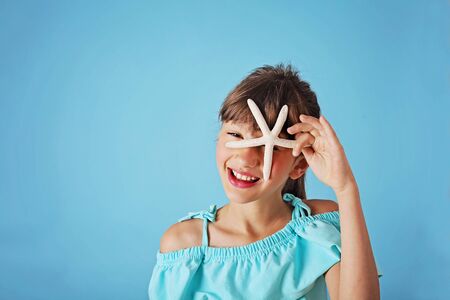 Smiling cute girl with seashell in the studio. Summer and vacations concept.の写真素材