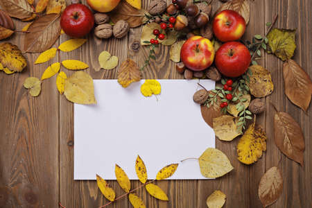 colorful leaves, pumpkin, nuts, apples and mushrooms on wooden background