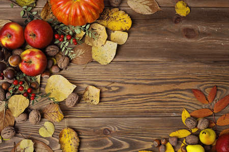 colorful leaves, pumpkin, nuts, apples and mushrooms on wooden background