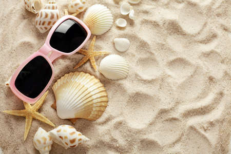 sunglasses and seashells on sand beach backgroundの写真素材