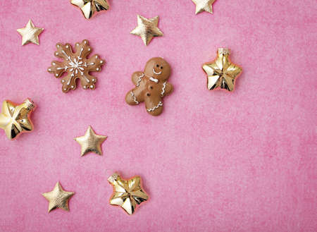 seasonal decoration. shiny gold christmas stars and gingerbread cookies on paper pink background...
