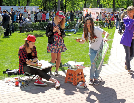 Drawing late teens students on the open outdoors lesson of art school among the citizens on the city square during the Victory Day celebrationのeditorial素材
