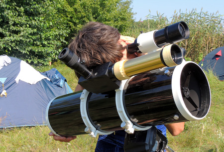 The man watching the sky through a telescope at the campsiteの写真素材