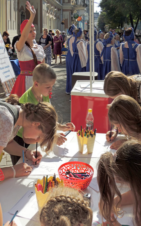 Pre-adolescen and early teens children are engaged in painting in the city street among the townspeople during the celebration of the City Dayのeditorial素材