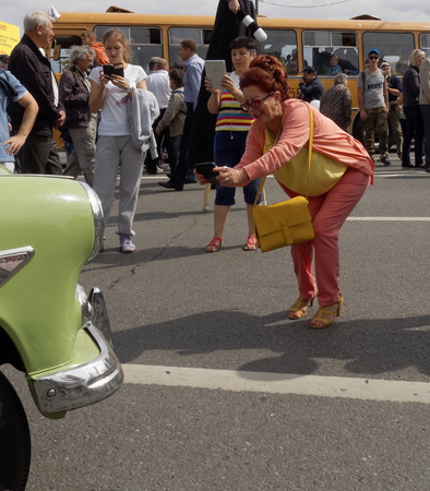 Bent woman studiously photographing an retro carのeditorial素材