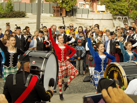 Girls dancing during show of Celtic pipes and drums band surrounded by townspeople in the Park of arts "Muzeon" on the Crimean embankment, Moscow. Festival of military orchestras "Spasskaya Tower".のeditorial素材