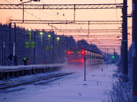 A local train leaves the suburban platform early in the winter morning in the light of the rising sun.の写真素材