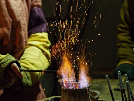Sparks from the fire and a blacksmith's hand with a poker at night